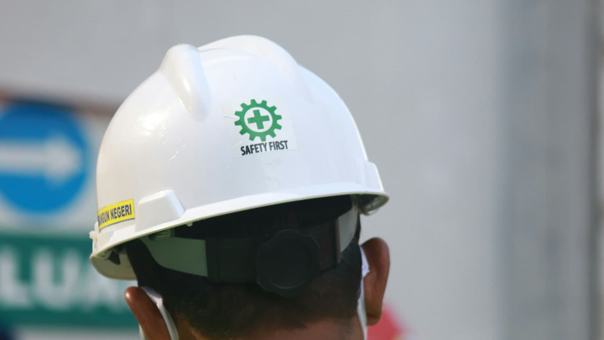 Worker in safety vest and helmet, seen from behind